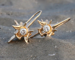 14k gold rattlesnake vertebrae earrigns with white diamond on beach