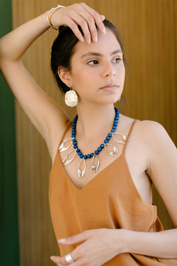 Female model wearing lunaria seed pod earrings and rattlesnake jawbone multi necklace